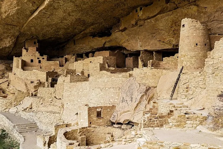 A multi-level ancient stone settlement nestled within a cliff overhang.